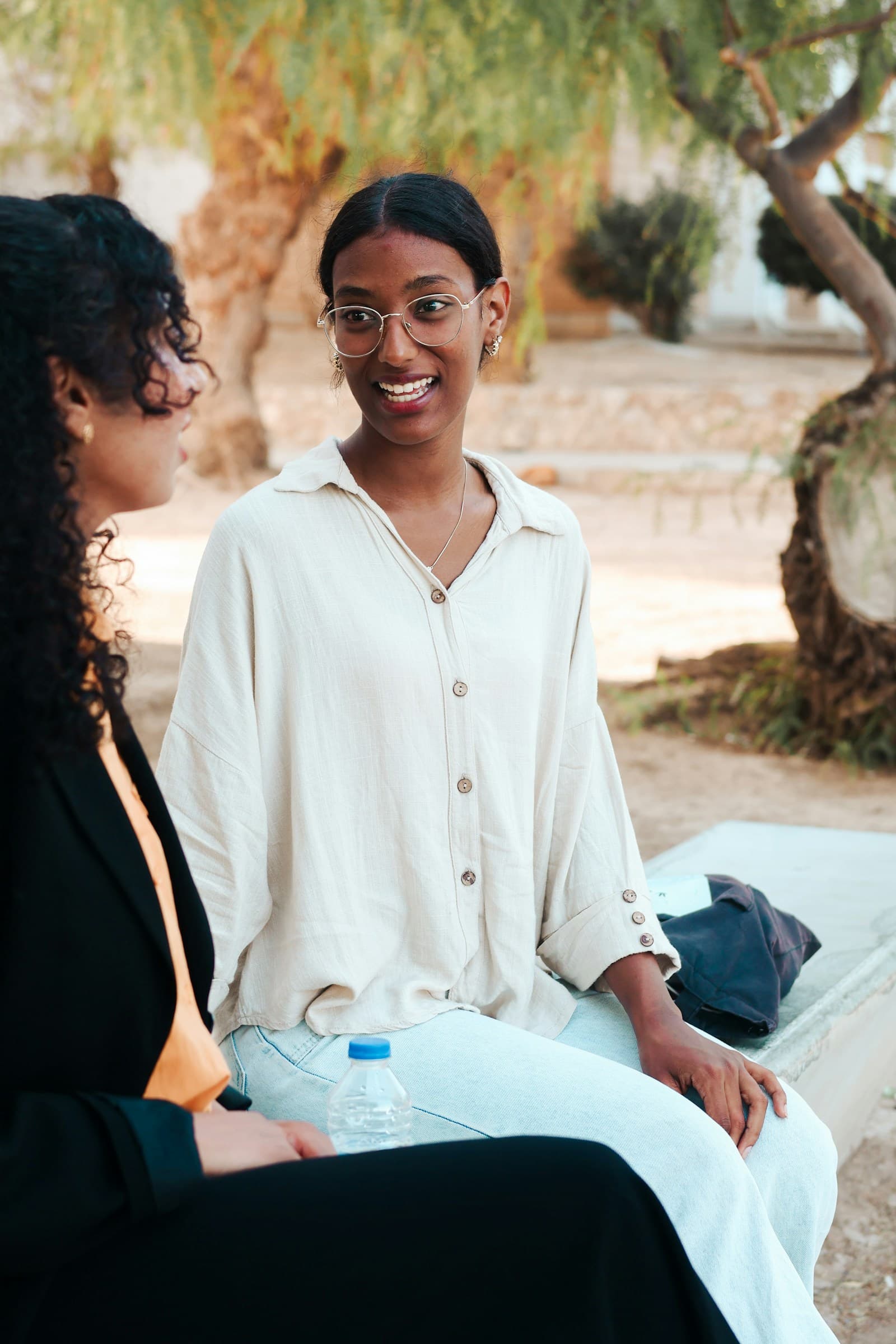 Two women talking together outdoors under a tree